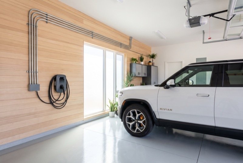 Level 2 EV charger mounted in a garage beside an electric SUV