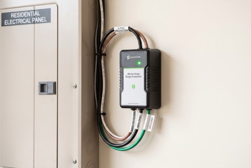 Whole-home surge protector installed beside a residential electrical panel